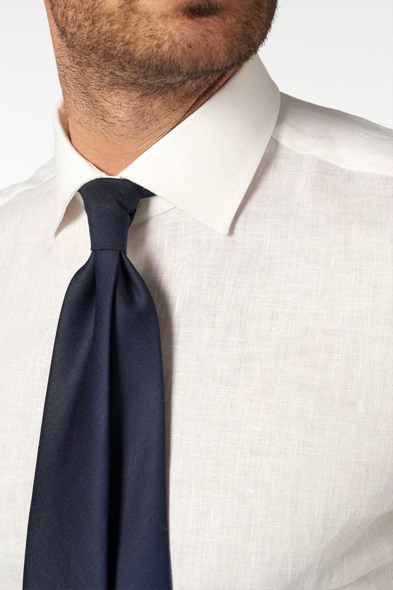 Camicia bianca su misura senza taschino, indossata con cravatta blu