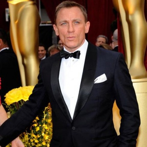 L'attore Daniel Craig indossa uno smoking nero, camicia bianca e pochette bianca ripiegata a punta.
