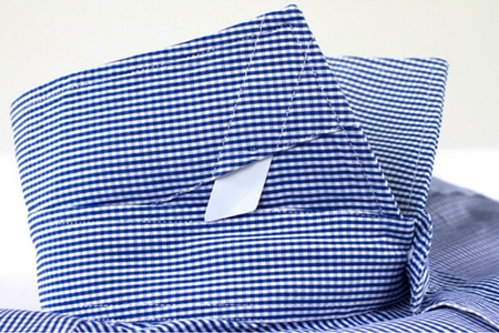 Close up on collar plastic removable white stays of a checkered dress shirt
