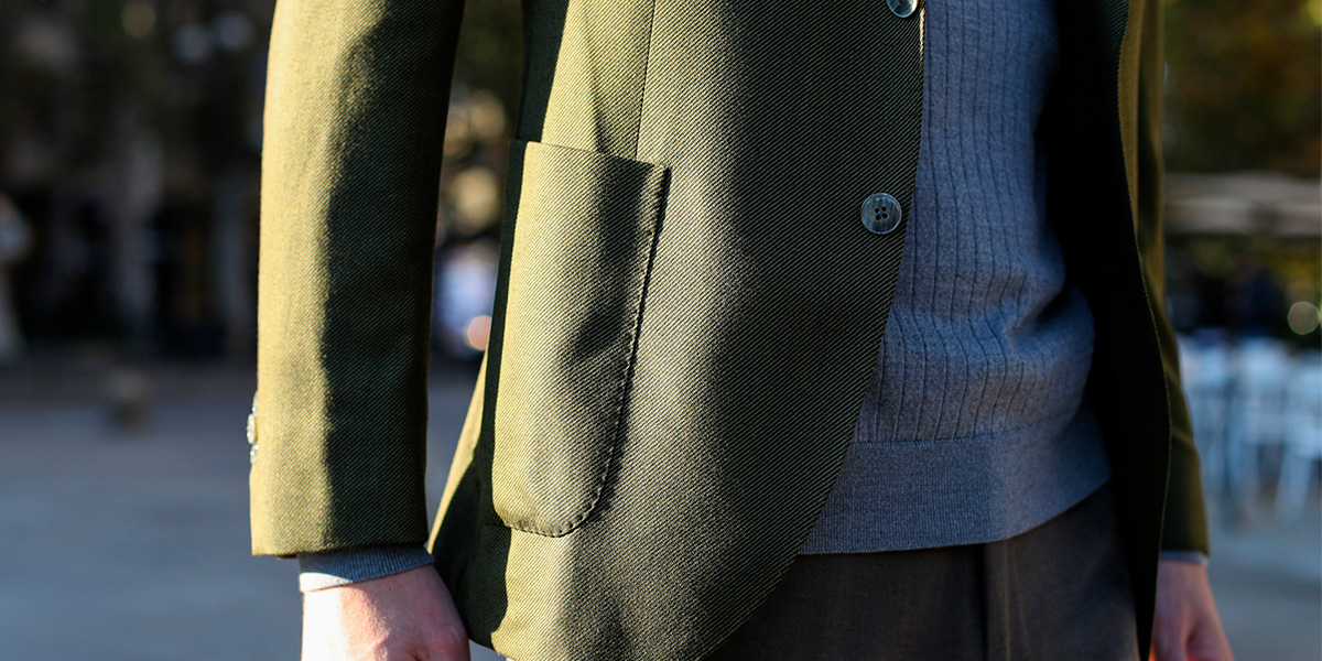 Details of a Lanieri tailored green blazer on a light blue ribbed sweater