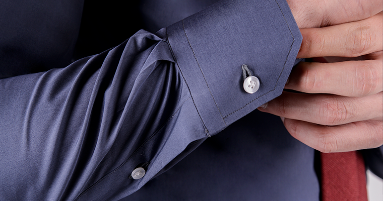 Close up on mitered cuff of a tailored cotton blue men's dress shirt