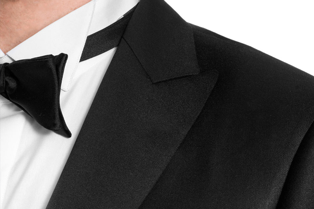 Détail sur les revers en pointe d'un smoking, porté avec un nœud papillon noir et une chemise à col diplomate à rabats