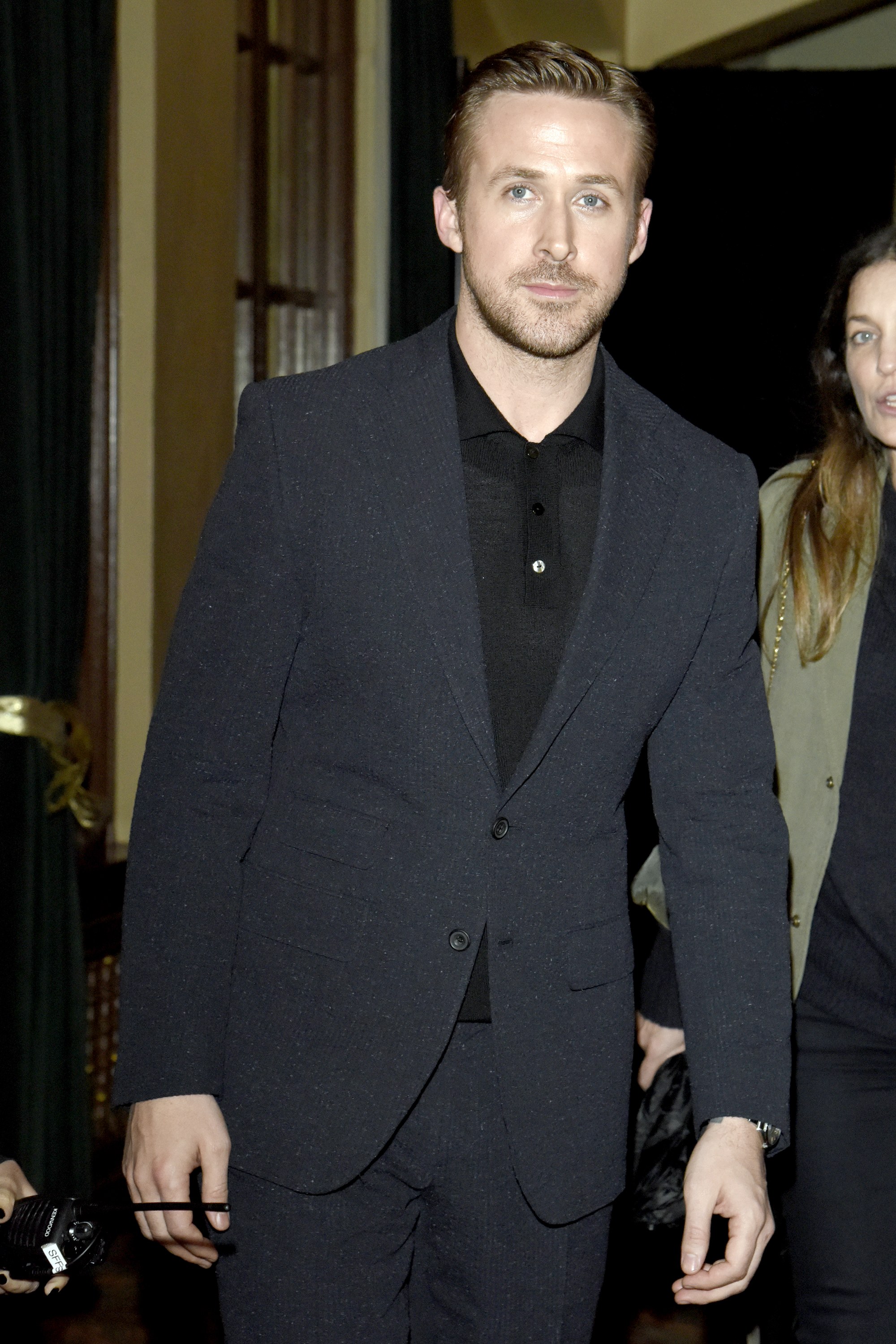 Actor Ryan Gosling wears a black polo shirt under a dark gray suit