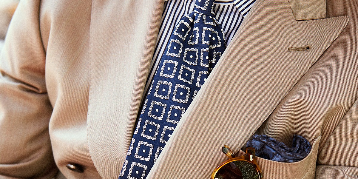 Dettaglio look abito solaro con cravatta fantasia e camicia a righe