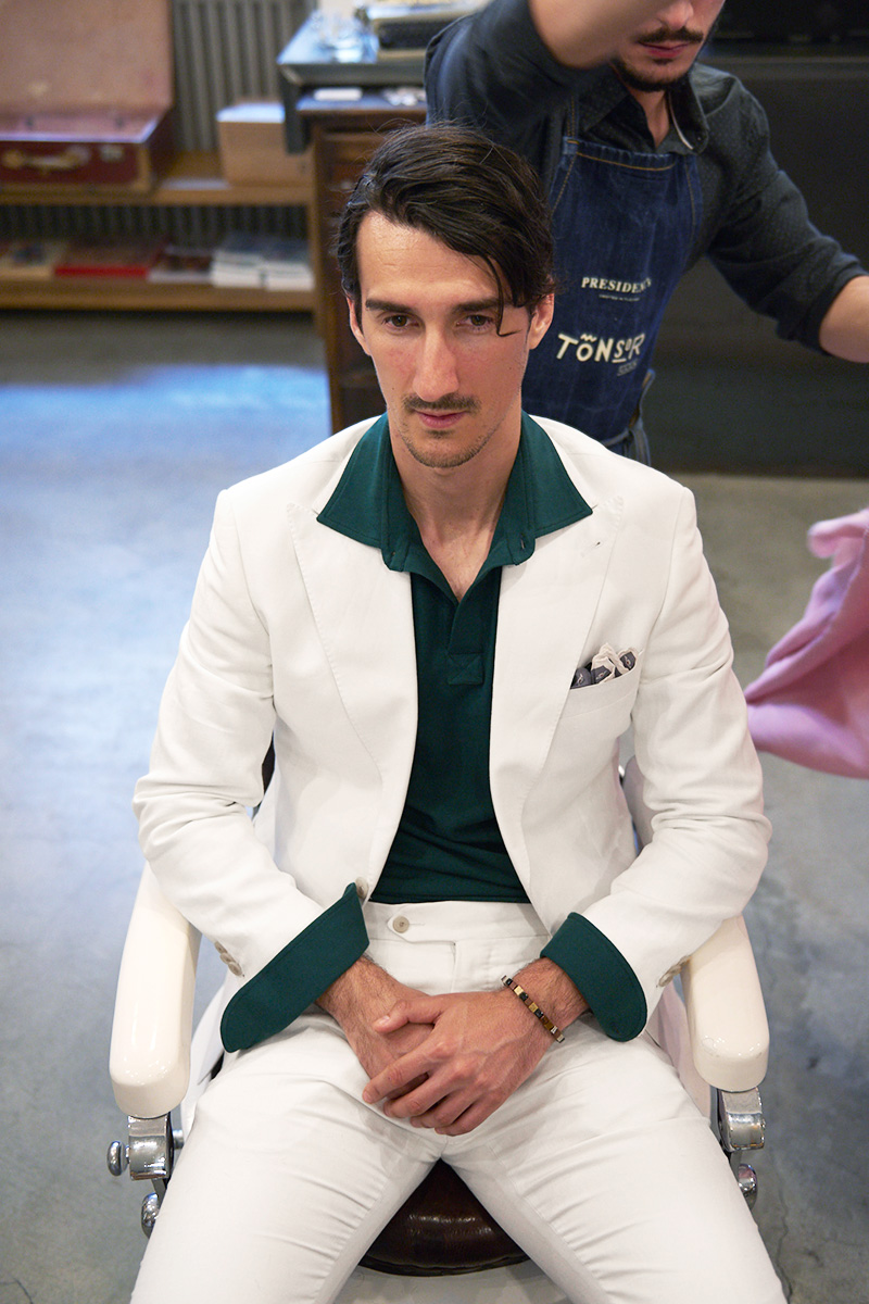 Uomo indossa abito bianco su misura con polo verde dal barbiere