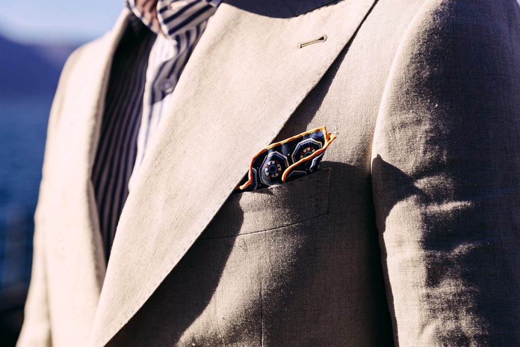 Detail on beige jacket with puff fold folded blue pocket square