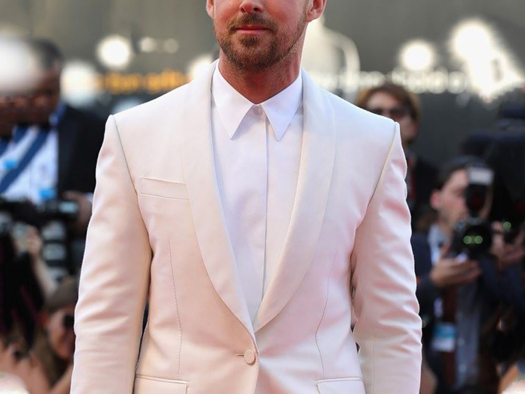 A man wears a white tuxedo, a white shirt without a bow tie