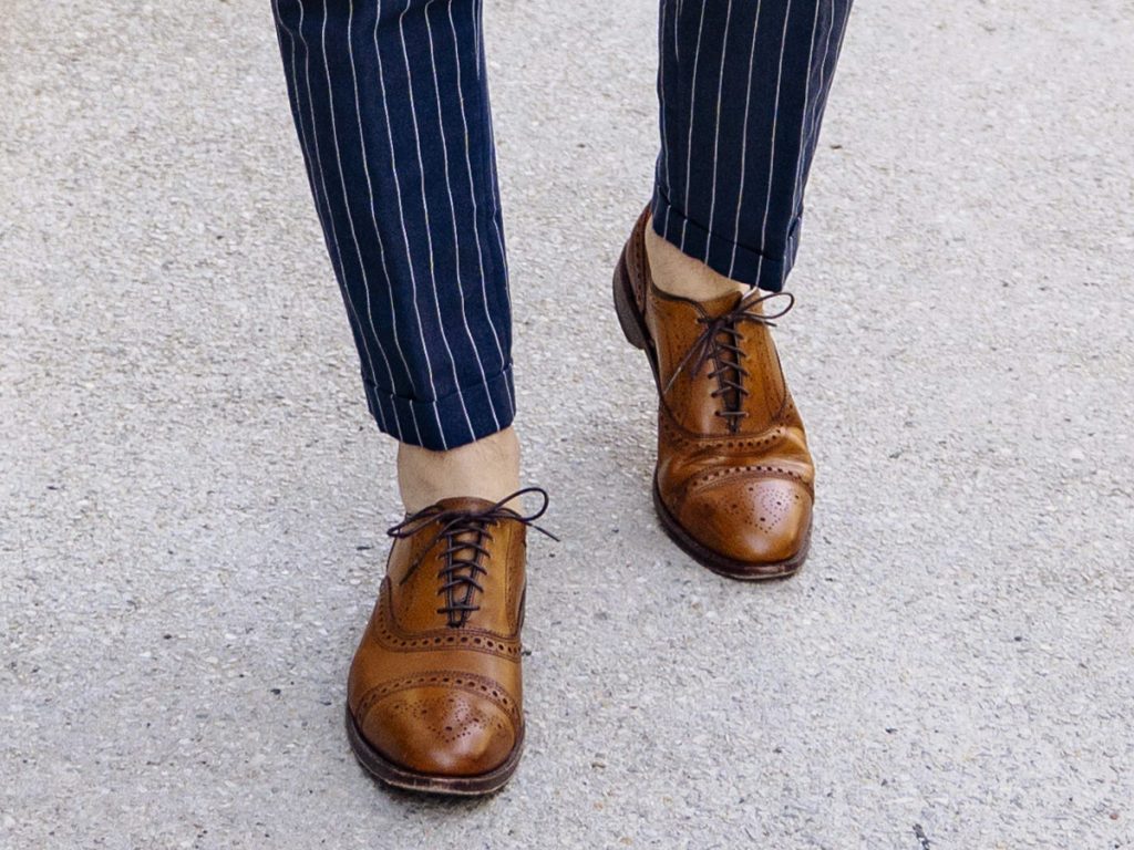 Un paio di scarpe marroni da uomo indossate senza calze