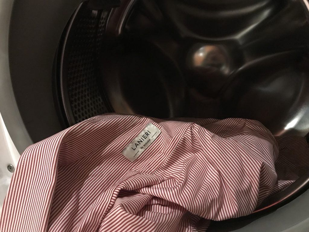 Chemise en laine rayée rouge et blanche devant un tambour de machine à laver